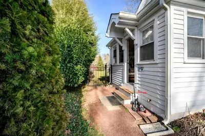 a white house with a gate next to a yard at Charming Historic Riverfront Home with Garden Views near Lambertville, New Jersey in Titusville