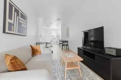 a living room with a couch and a flat screen tv at Blueground Alphabet City washer nr Tompkins Square Park NYC-2160 in New York
