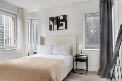 a white bedroom with a bed and two windows at Blueground Midtown South rooftop nr Bryant Park NYC-2031 in New York
