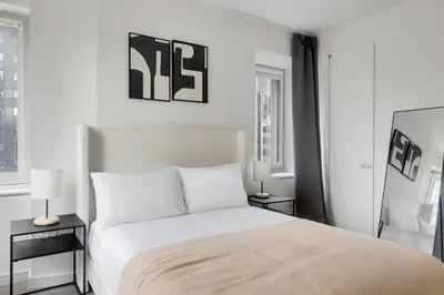 a white bedroom with a bed and two lamps at Blueground Midtown South rooftop nr Bryant Park NYC-2031 in New York