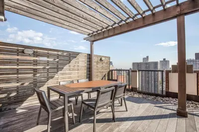 a patio with a wooden table and chairs on a balcony at Blueground Upper West Side fitness nr Central Park NYC-1993 in New York