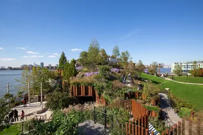 a garden with flowers on a hill next to the water at Chelsea 1BR w Water views Doorman NYC-210 in New York