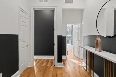 a hallway with a black door and a mirror at Apartmint at 113 Chestnut - Philadelphia in Philadelphia