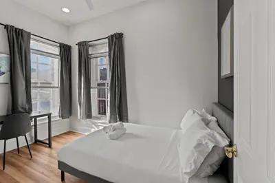 a white bedroom with a bed and a desk and window at Apartmint at 113 Chestnut - Philadelphia in Philadelphia