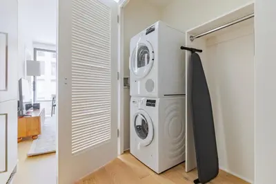 a laundry room with a washer and dryer next to a door at Blueground Chelsea rooftop pool nr The Vessel NYC-2147 in New York