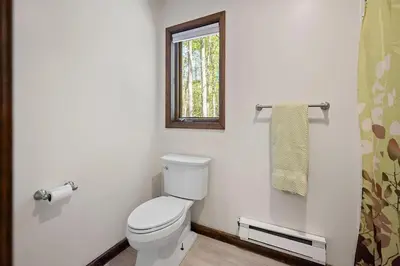 a white bathroom with a toilet and a window at Lake Naomi Retreat Family Fun & Games in Pocono Pines