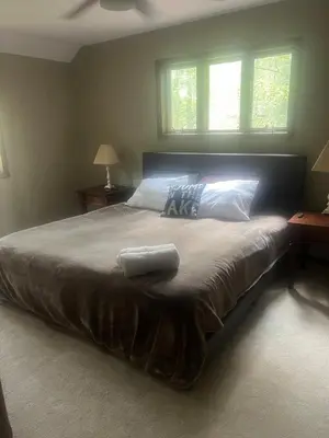 a large bed in a bedroom with two windows at Lake Naomi Retreat Family Fun & Games in Pocono Pines