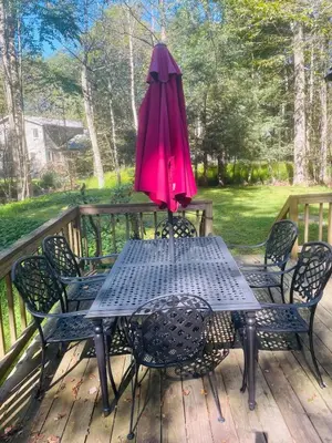 a table with a pink umbrella and chairs on a deck at Lake Naomi Retreat Family Fun & Games in Pocono Pines