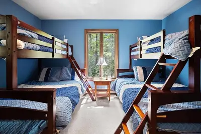two bunk beds in a room with blue walls at Lake Naomi Retreat Family Fun & Games in Pocono Pines