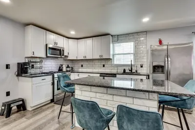 a kitchen with white cabinets and blue chairs at 4 Mi to MetLife Stadium Modern Retreat! in Wallington