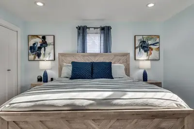 a bedroom with a large wooden bed with blue pillows at 4 Mi to MetLife Stadium Modern Retreat! in Wallington