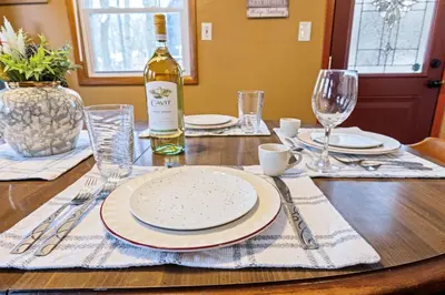 a table with a bottle of wine and a plate at Hot Tub + Fire Pit • Game Room • Community Pool in Tobyhanna