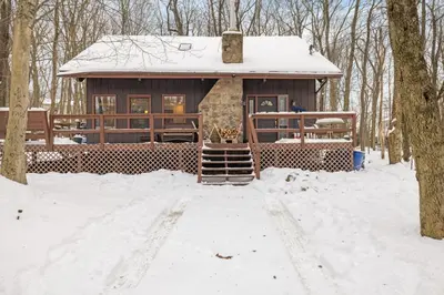 a cabin in the woods in the snow at Hot Tub + Fire Pit • Game Room • Community Pool in Tobyhanna