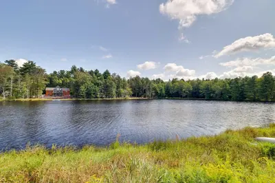 a large lake with a house in the background at Fire Pit, Games and Outdoor Fun! Poconos Retreat in Blakeslee