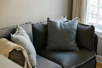 a gray couch with pillows in a living room at The Citizen Suite - Downtown in Lancaster