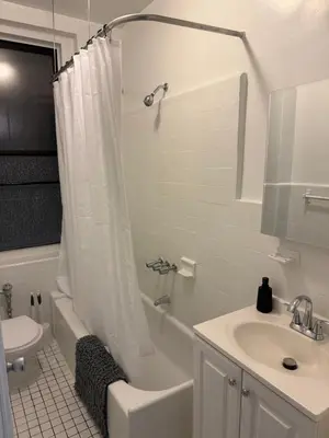 a white bathroom with a shower curtain and a sink at The Broadway Escape - Private Room in Times Square in New York