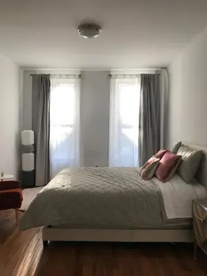 a bedroom with a large bed with two windows at Cosy apartment in prime West Village in New York