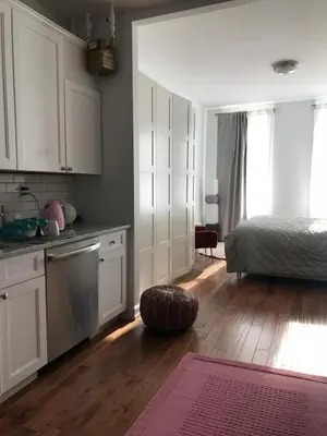 a kitchen with white cabinets and a bed and a wooden floor at Cosy apartment in prime West Village in New York
