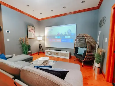 a living room with a couch and a big screen tv at IceCream - Pool Table - 120 Projector - King Bed in Philadelphia