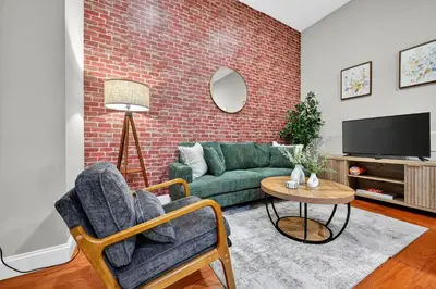 a living room with a green couch and a brick wall at Luxury 3 Bedroom - Perfect Center City Location - 501 in Philadelphia