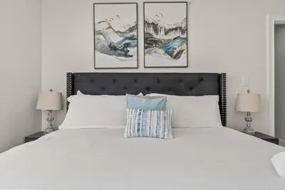 a bedroom with a white bed with three paintings on the wall at Skyline Escape in Philadelphia Chic & Bright in Philadelphia