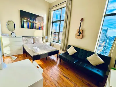 a living room with a couch and a guitar on the wall at Modern Luxury Executive Room with NYC Fast Access in Paterson