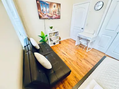a living room with a black leather couch and a table at Modern Luxury Executive Room with NYC Fast Access in Paterson