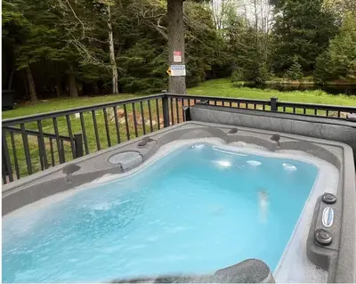 a hot tub with blue water in a backyard at 6bds|Secluded|Pool|Hot tub|Sauna|Games|Movie in Long Pond
