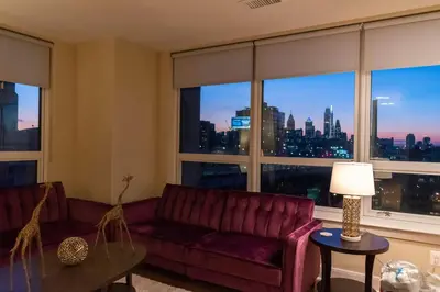 a living room with a red couch and a large window at Stay Like A Boss- Penthouse-Views- Convention Center- Free Parking in Philadelphia