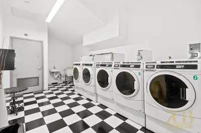 a laundry room with four washing machines on a checkered floor at 517 - 47C Beautifully Renovated 1 bedroom in Prime Manhattan in New York
