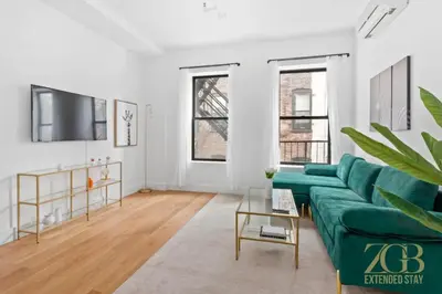 a living room with a green couch and a tv at 517 -41D Gorgeous and Fully Equipped Luxury 1 Bedroom Apt in New York