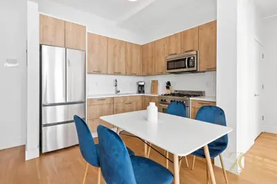 a kitchen with a white table and blue chairs at 517 -41D Gorgeous and Fully Equipped Luxury 1 Bedroom Apt in New York
