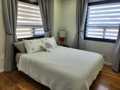 a bedroom with a white bed with two windows at Luxury Floral Loft with Balcony Near MetLife & NYC in Bogota