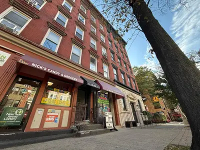 a red brick building with a store on a street at A Luxury Apartment in the Heart of Hoboken in Hoboken