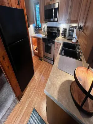 a kitchen with a black refrigerator and wooden cabinets at Lakefront Paradise near everything! in Hawley