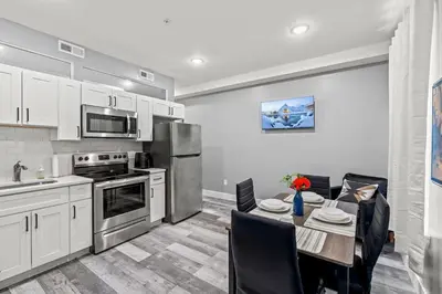 a kitchen with white cabinets and a table with chairs at Elegant 1BR Stay Near Zoo & Downtown Philly in Philadelphia