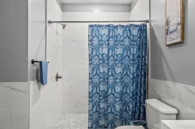 a bathroom with a shower with a blue shower curtain at Elegant 1BR Stay Near Zoo & Downtown Philly in Philadelphia