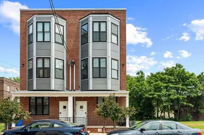a building with two cars parked in front of it at Elegant 1BR Stay Near Zoo & Downtown Philly in Philadelphia