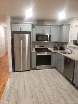 a kitchen with stainless steel appliances and white cabinets at Deluxe 3 bedroom in Newark