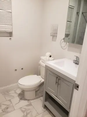 a white bathroom with a toilet and a sink at Deluxe 3 bedroom in Newark