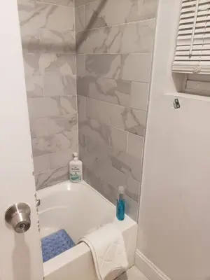 a bathroom with a bath tub with marble walls at Deluxe 3 bedroom in Newark