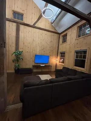 a living room with a couch and a flat screen tv at Spacious Barn House experience! in Hellertown