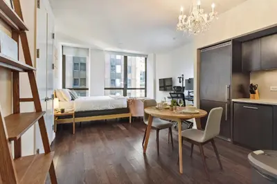 a living room with a table and a bedroom at FiDi Studio w Work Setup by Anyplace - 10250 in New York