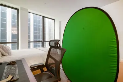 a green surfboard sitting in a room with a bed at FiDi Studio w Work Setup by Anyplace - 10254 in New York