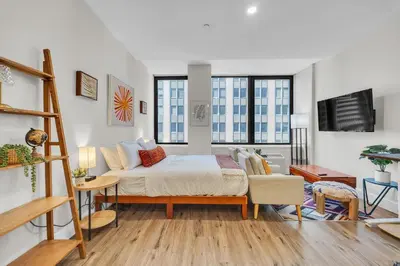 a bedroom with a bed and a couch and windows at FiDi Studio w Work Setup by Anyplace - 11679 in New York