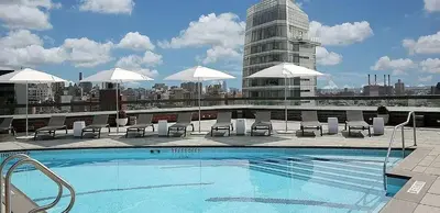 a swimming pool with chairs and umbrellas on a building at Noho Luxury Building 1Br with Living room with Pool and First Floor in New York