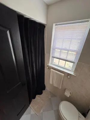 a bathroom with a black shower curtain and a toilet at 30 min from NYC luxury and chic 3 bedroom in Harrison