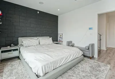 a bedroom with a large bed and a black brick wall at The Executive Penn's Landing - High End Luxury 3BR-Sauna-Gym-Garage-Roof Deck in Philadelphia
