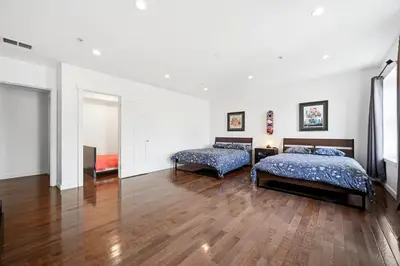 two beds in a large room with wooden floors at Beautiful 4th Floor Walk-Up Apartment in Old City in Philadelphia