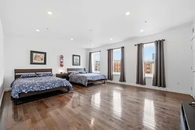 two beds in a bedroom with wood floors and windows at Beautiful 4th Floor Walk-Up Apartment in Old City in Philadelphia